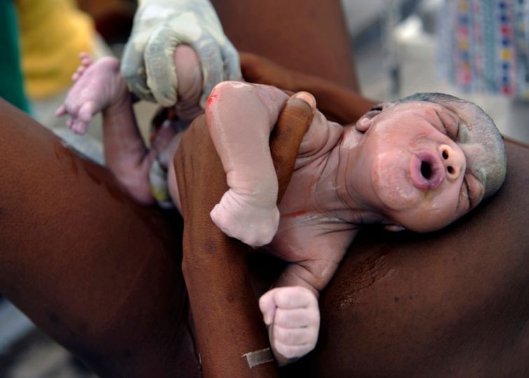 'Life Goes On' A tiny new life emerges as Destiny Ariel Dorival grimaces at her mother, Nehemie Hilaire, 39, minutes after being born in a makeshift tent serving as a maternity unit at the General Hospital in Port-au-Prince. Nearly half of Haiti's population is younger than 18 years old. Even in better times, many of this country's youth were in desperate need of aid (Nikki Kahn, The Washington Post - March 16, 2010)