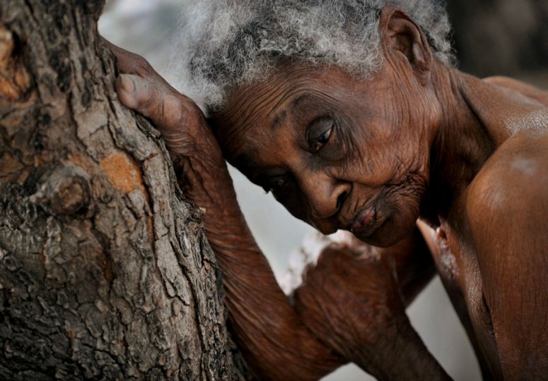 'The Elderly' Idamise Pierre leans against a tree, her withered skin resembling its bark, as she waits to bathe at the Azil Communal Home for the Aging. With weary resignation, the elderly have endured decades of Haiti's poverty and political turmoil and in their twilight years are now left with heavy hearts by the earthquake that eternally altered their lives. (Nikki Kahn, The Washington Post - March 13, 2010)