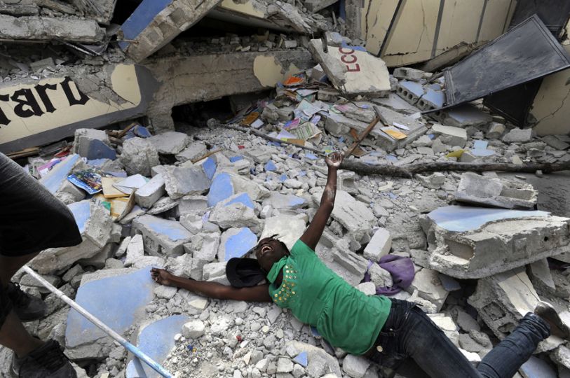 'Shattered Lives' Caked in the dust of crushed plaster and cement, Haitians dug out family members by hand and piled bodies on street corners as clusters of bloodied and dazed survivors pleaded for help. Cindy Tersme throws herself amid the rubble of Ecole St. Gerard, screaming in anguish as she searches for her brother Jean Gaelle Dersmorne, 14. 'I can see my brother's feet but can't pull him out,' she said, weeping. (Carol Guzy, The Washington Post - January 15, 2010)