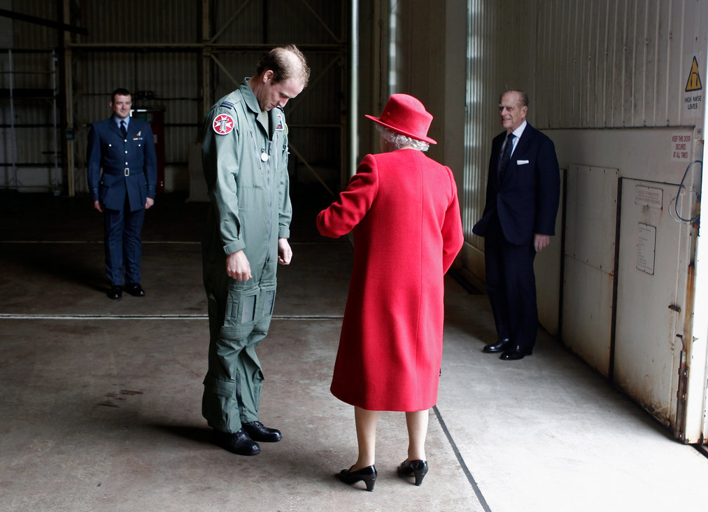 The Prince and his Grandmother. u201dQueen Elizabeth II, in red, was visiting a Royal Air Force base in Wales, where she was greeted by her grandson, Prince William, who is stationed there as a search-and-rescue helicopter pilot. The gentleman to the right, in the blue suit, is the Queen's husband, and William's grandfather, Prince Philip. The queen, rightly, seems to be in charge.u201d Photo by Christopher Furlong, u201dLensu201d, New York Timesrn
