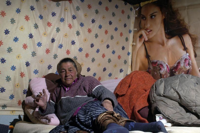 Lucretia, 62 ans dans sa cabane. Décor de publicité commun aux maisons de ce terrain. © Gabriela Lupu