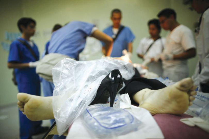 Rodrigo Abd, In this photo taken Nov. 25, 2010, medical staff look at a woman who died of gunshot wounds a few minutes after arriving to the emergency room of the San Juan de Dios hospital in Guatemala City, Guatemala. According to fire fighters, the woman was shot after she left her job.