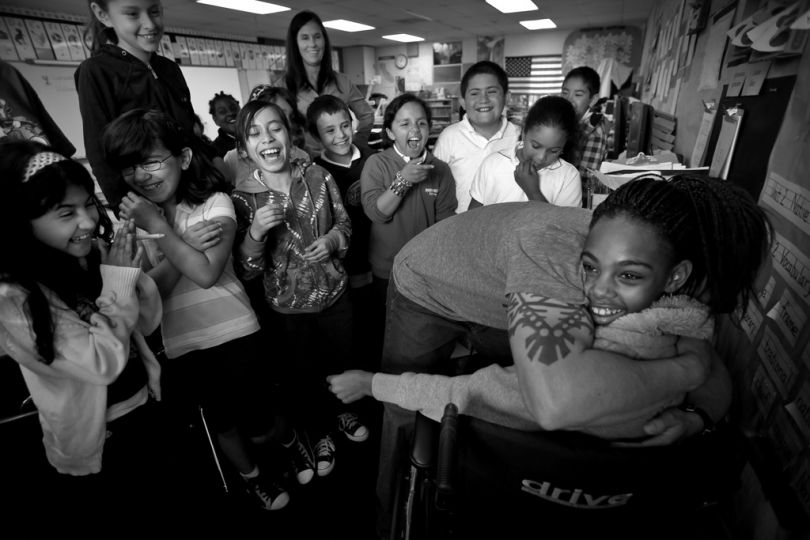 Returning to school after a months absence from being shot, Erica Miranda, 10, gets a bear hug from one of her teachers as students look on and giggle. --We're glad to have you back, Erica,-- her classmates said. --We prayed for you.-- © Barbara Davidson