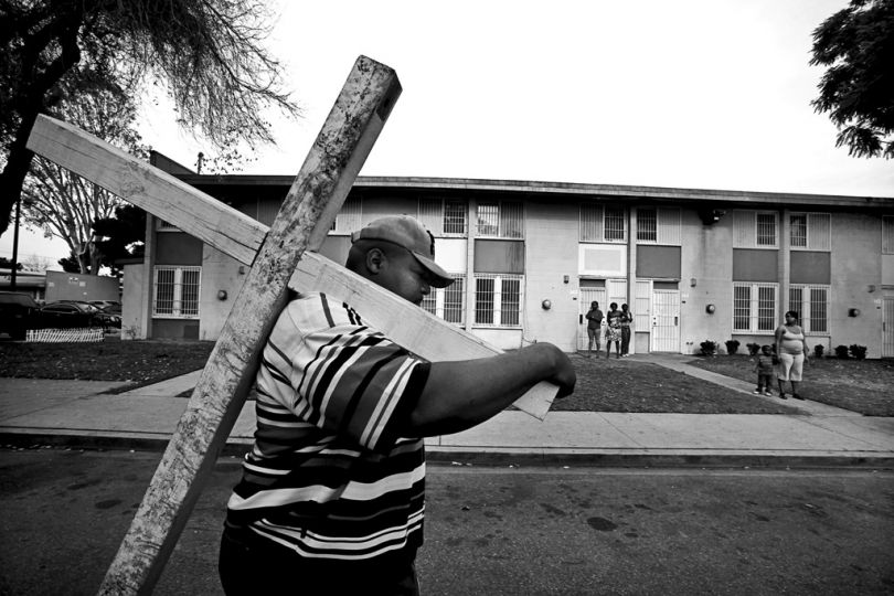 Pastor Wyman Jones, of Sweet Hill Baptist Church in South Los Angeles,  carries a wooden cross through the Nickerson Gardens public housing complex to protest gang violence.  Police have said the recent violence was linked to a civil war of sorts within the Bounty Hunters, for years the dominant gang in Nickerson Gardens, apparently over drug sales. © Barbara Davidson / Los Angeles Times