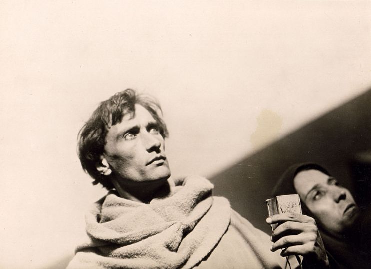 Jean Soulat - Maurice Boussus. Antonin Artaud. Photographie n & b réalisée lors du tournage du film de Carl Th. Dreyer La passion de Jeanne d'Arc, 1927. Tirage d'époque 16 x 22 cm (16,8 x 22,9 cm marges comprises). Au verso, tampon Collection André Bernard. rnProvenance : collection de l'historien d'art André Bernard. rnC'est une image de l'interrogatoire de Jeanne en place publique, en présence de Jean Massieu (Artaud), devant une foule surtout composée de femmes et d'enfants (plans 874 et suivants, après l'intertitre 122 : Il n'y a plus rien à faire... allez avertir le bourreau !, déclaration de Cauchon).rnLa photographie a été prise en contre-plongée et en oblique, dans l'esprit des prises de vues de Dreyer avec son chef opérateur Rudolph Maté.rn