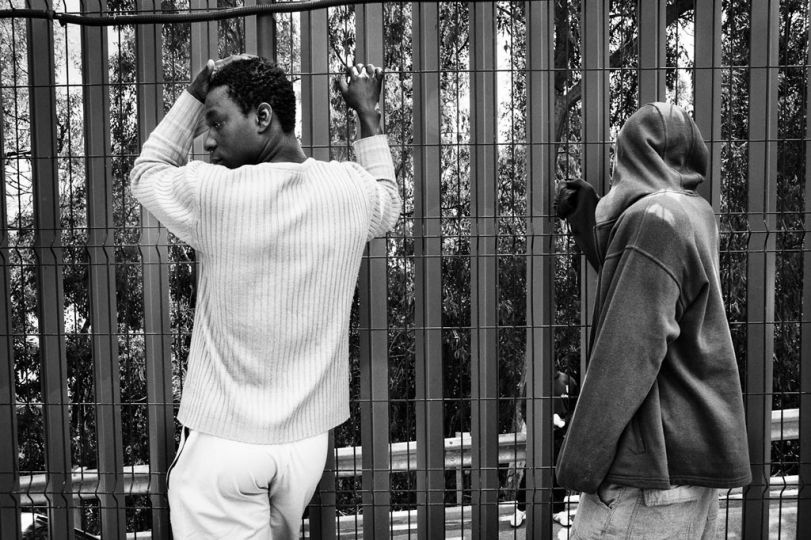 Spain, Ceuta, April 10 2012. Two guests of CETI killing time around the fence of the centre. © Gianfranco Tripodo