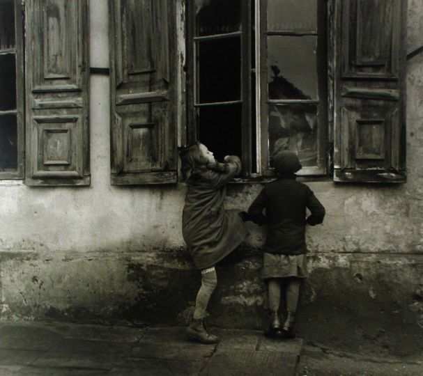 These girls were sent out to play, but they preferred to watch Mother at work inside, Slovakia, 1935 Gelatin silver print; printed later 11 x 14 inchesrNumeric annotations in pencil on print verso. © Chim (David Seymour)/Magnum Photos