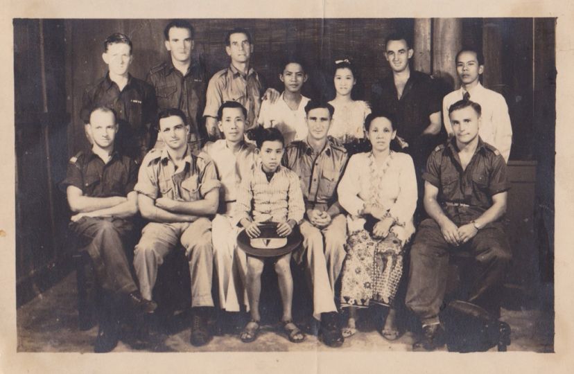 Two generations of the Ang family posing in a group photograph with British soldiers at River Valley Road Camp, Singapore, 1946