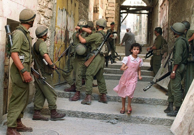 A Palestinian girl runs 11 October 1990 through a row of Israeli soldiers in Jerusalem's Old City as security has been increased following rioting that erupted in response to the killing of 21 Palestinians 08 October 1990.  AFP PHOTO PATRICK BAZ