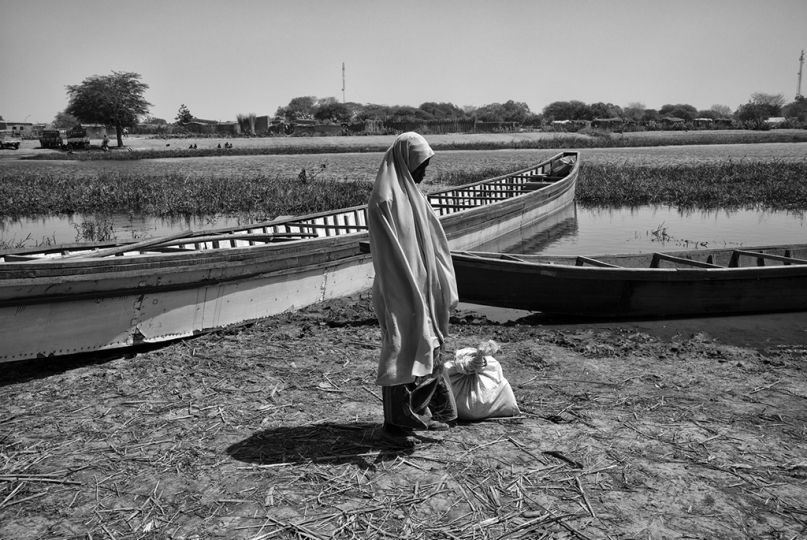 Une femme nigériane réfugiée à Ngouboua attend sur une rive du lac Tchad, le 11 février 2015, qu'on la transporte du camp de réfugiés où elle habite (situé sur une u00eele juste en face de Ngouboua) vers la terre ferme. Pour des raisons de sécurité, les autorités tchadiennes et le HCR tentent de transférer un maximum de réfugiés vers le camp de Dar-es-Salam, situé plus dans les terres et donc moins sujet aux attaques de Boko Haram.rnNgouboua a été la cible deux jours plus tard d'une attaque massive de Boko Haram ayant entrainé la mort de 5 personnes dont le chef de canton et l'incendie des deux-tiers du village.  © Olivier Laban-Matteirn