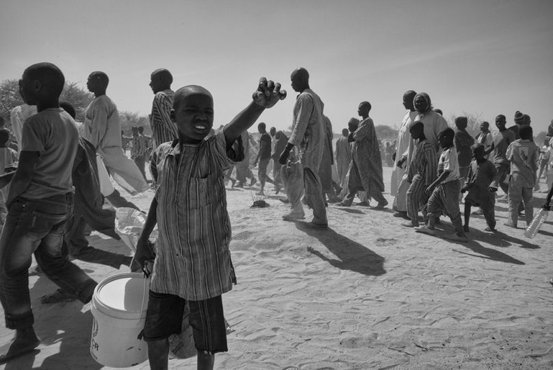 Des dizaines de réfugiés nigérians regagnent le centre du camp de Dar-Es-Salam, près du village de Baga Sola, sur les rives tchadiennes du Lac Tchad, le 8 février 2015, après s'être trompés de jour sur la distribution de leur première ration de nourriture. Ce jour-là, seules les familles de plus de 10 individus étaient servies. Les autres ont du00fb attendre le lendemain. © Olivier Laban-Matteirnrnrnrn