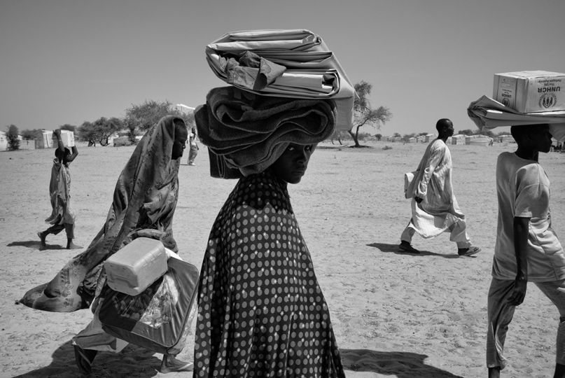 Kaltouma Abakar (C) traverse le camp de Dar-es-Salam, le 9 février 2015, pour rejoindre, avec sa famille, les deux abris qui leur ont été attribués, au lendemain de leur arrivée en pirogue sur une plage de Baga Sola (Tchad), à 12 km de là. © Olivier Laban-Matteirnrnrnrn