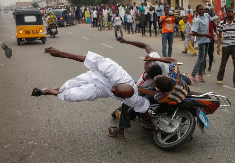 Elections in Nigeria © Goran Tomasevic / Reuters.
Two supporters of the presidential candidate Muhammadu Buhari and his All Progressive Congress party accidently hits  another supporter with their motorbike during celebrations in Kano, Nigeria March 31, 2015.  REUTERS/Goran Tomasevic  