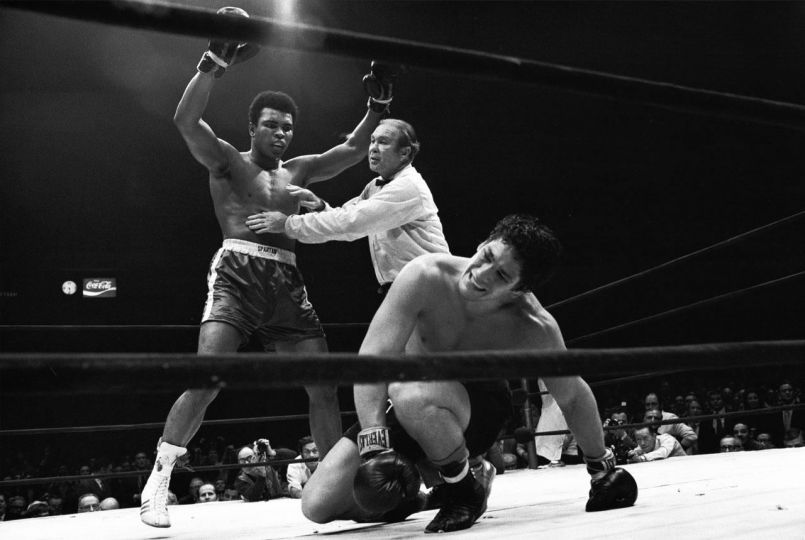 Neil Leifer (United States, b. 1942) NABF Heavyweight Title: Muhammad Ali victorious, getting held back by referee Mark Conn after knockdown of Oscar Bonavena during fight at Madison Square Garden. New York, NY, December 7, 1970 ©Neil Leifer/Courtesy Peter Fetterman Gallery, Santa Monica