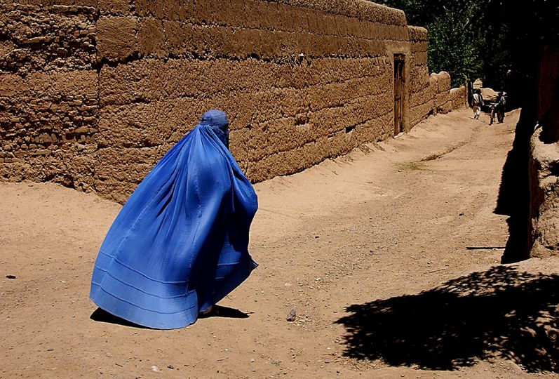 An Afghani woman hurries through the streets of Gardez, as a U.S. military convoy passes her on their way to Bagram, Afghanistan, on May 11, 2002, in support of Operation Enduring Freedom. The convoy is on its way back to Bagram after dropping off members from the 345th Psychological Operation Company, Dallas, Texas, in Gardez. The team will be the first in the area completing their mission of visiting local villages and towns promoting Afghanistan and American coalition cooperation and to gather intelligence.