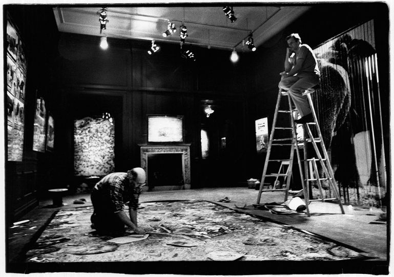 From the stepladder, Beard watches Israel arrange artwork on floor of the museum © Orin Langelle