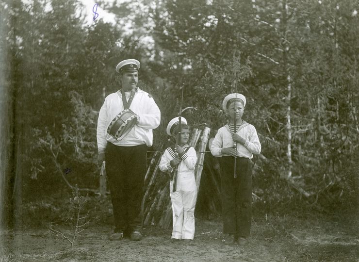 «Scouting». Tsarevich Alexei, his «Uncle» — boatswain A. E. Derevenko, and his mate from the school of cabin boys. «В разведке». Цесаревич Алексей со своим дядькой боцманом А. Деревенько и товарищем из школы юнг Skerries, 1909 Russian State Archive of the Navy