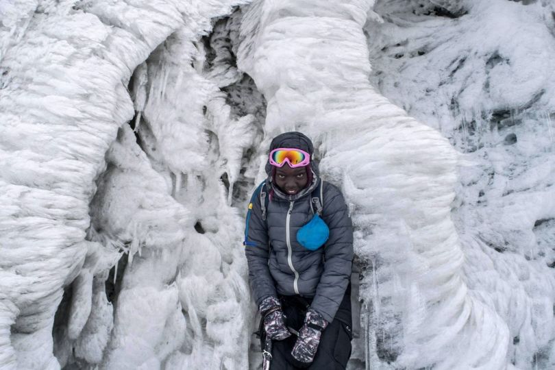 © Timothy Latim, Overall Winner, 1st Place, Portrait. Summiting Margherita
A climber pauses to pose for a portrait in front of a wall of ice near the summit of Margherita Peak, the highest of the Rwenzori mountain range.