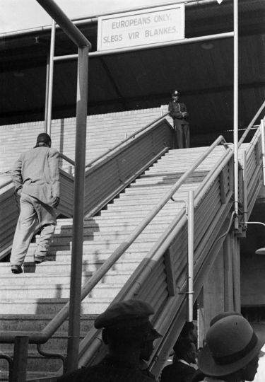 David Goldblatt, The first apartheid signs segregating facilities at Johannesburg railway station: a Black man who had used these stairs many times before is turned back after being told by a policeman that they are for 