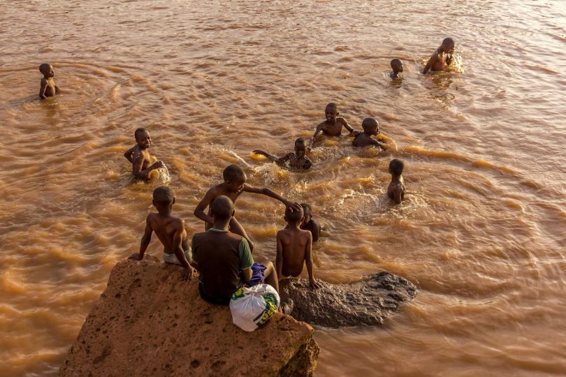 Kibera: Stories From Within © Brian Otieno 1st Place - Kids swimming in the murky and obscure brown waters formed as a result of an ongoing road.