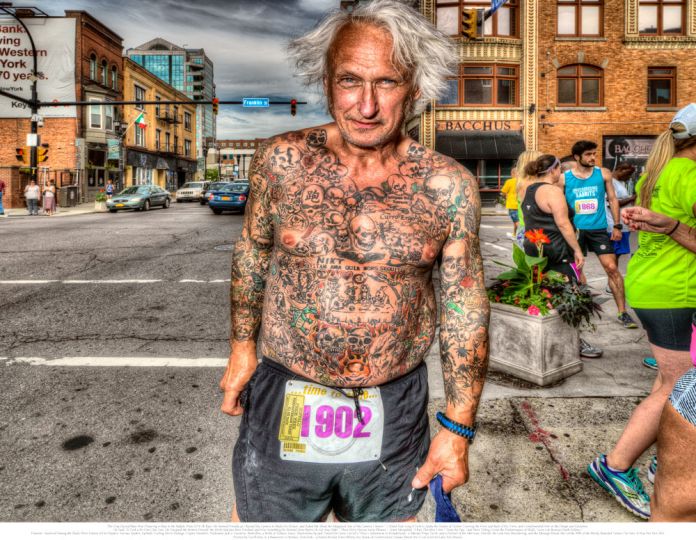 2. The Gray Haired Man Was Preparing to Run in the Buffalo Pride 2016 5K Race. He Seemed Friendly as I Raised My Camera to Make His Picture, and Asked Me About the Megapixel Size of My Camera’s Sensor. I Asked How Long It Took to Apply the Dozens of Tattoos Covering the Front and Back of His Torso, and Complimented Him on the Design and Execution. He Said: “It Took a Bit Over One Year; He Designed the Pattern Himself; the Work Had Just Been Finished; and Was Something He Wanted Done Before He Got Any Older.” Closely Read, There Were Various Latin Phrases—Some Misspelled: “I Run Therefore I Am;” “Seize the Day;” and Most Telling, Given the Predominance of Skulls, “Love Life Because Death Follows.” However, Scattered Among the Skulls Were Tattoos of Hot Peppers, Various Spiders, Eyeballs Trailing Nerve Endings, Cryptic Numbers, Halloween Jack-o’-Lanterns, Butterflies, a Bottle of Tabasco Sauce, Illustrations by Jack Tenniel for Lewis Carroll’s “Alice’s Adventures in Wonderland,” a Mutant Ninja Turtle, and a Portrait of Jim Morrison. Overall, the Look Was Bewildering, and the Message Mixed. But Unlike 98% of the Mostly Retarded Tattoos I’ve Seen, It Was Not Pure Shit. © Les Krims