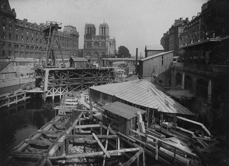 Chemin de fer métropolitain municipal de Paris, ligne de la Porte de Clignancourt à la Porte d'Orléans, 1905-1909, tome 4. 242 : Traversée de la Seine au Châtelet. Jonction des caissons du petit bras et raccordement sur la rive gauche. Vue générale des chantiers vers l'amont de la Seine. Notre-Dame de Paris ; Préfecture de police . Paris (IVème arr.). Photographie de Charles Maindron (1861-1940), 28 mai 1909. Paris, bibliothèque de l'Hôtel de Ville.