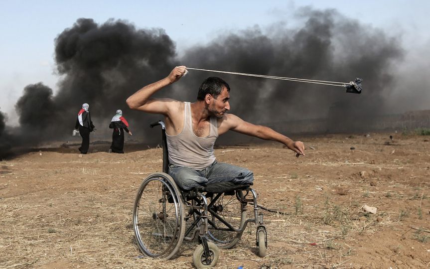 Palestinian Saber al-Ashkar, 29, hurls rocks during clashes with Israeli forces along the border with the Gaza strip, east of Gaza City, on May 11, 2018, as Palestinians demonstrate for the right to return to their historic homeland in what is now Israel. © Bayeux Award photo 2018 – Mahmud Hams / AFP - Le Palestinien Saber al-Ashkar, 29 ans, lance des pierres durant des affrontements contre les forces israéliennes, le long de la frontière de la bande de Gaza à l’Est de la ville de Gaza, le 11 mars 2018. Les Palestiniens manifestent pour le droit au retour dans leur terre d’origine, désormais considérée comme territoire israélien © Prix Bayeux Calvados-Normandie photo 2018 – Mahmud Hams / AFP