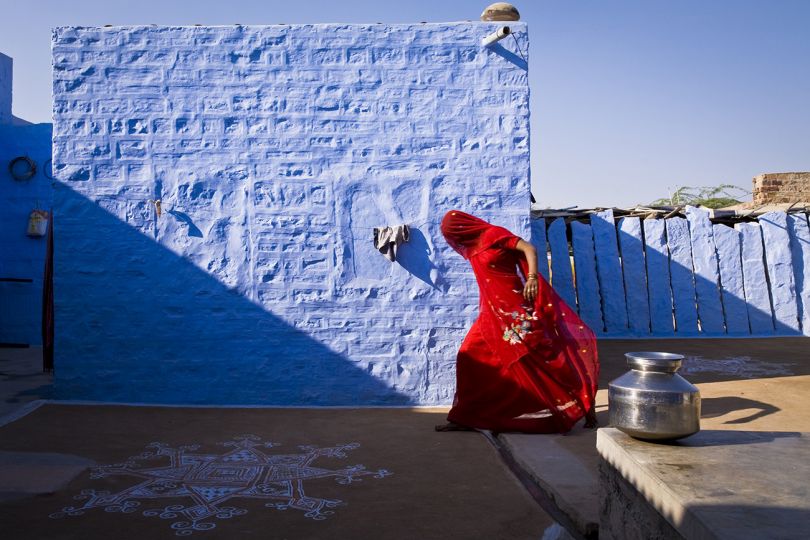A women does the house work, collecting water and dung, sweeping the backyard of her employer's home in Salawas village, rural Rajasthan, India © Christopher Pillitz 