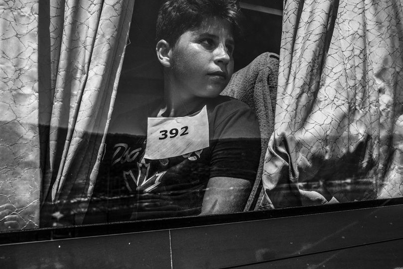 A Syrian boy sits in the coach that will take him to a CPA (Centro di Prima Accoglienza), a reception centre for migrants. Vibo Valentia, Italy, 28 August 2015. © Francisco Zizola