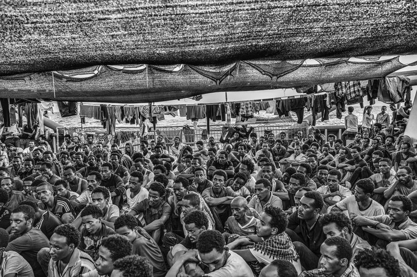 Eritrean migrants - the vast majority of the migrants rescued the day before off the Libyan coast - gather on the deck of the Bourbon Argos to attend the service performed by one of the three priests on board. 3 September 2015. © Francisco Zizola