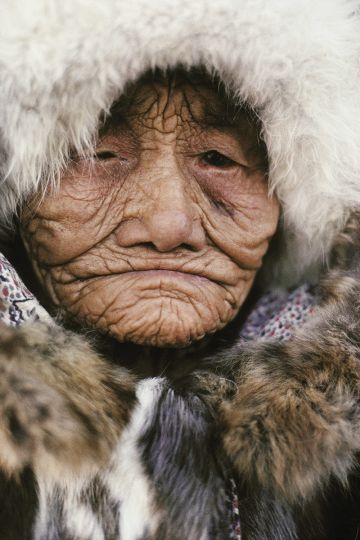 [Elle vit depuis seulement deux ans au village, dans un immeuble. Tous les matins, elle descend casser son bois dans la rue pour rester en forme !] Akoulina, 109 ans, eleveuse de rennes evenki, a passe toute sa vie au campement, dans la taiga. Jilinda. Yakoutie, mars 1990 © Marc Garanger