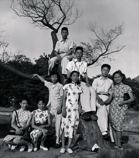 Photographer Zhou Haiying (sitting in the tree wearing glasses) joins with his stylish entourage of friends for a group portrait. The elegant qipaos, and Oxford Brogues are the height of Shanghai style during this era. Immediately below Zhou, is his wife Ma Xinyun, flanked by neighbours and friends. 1947 ©Zhou Haiying