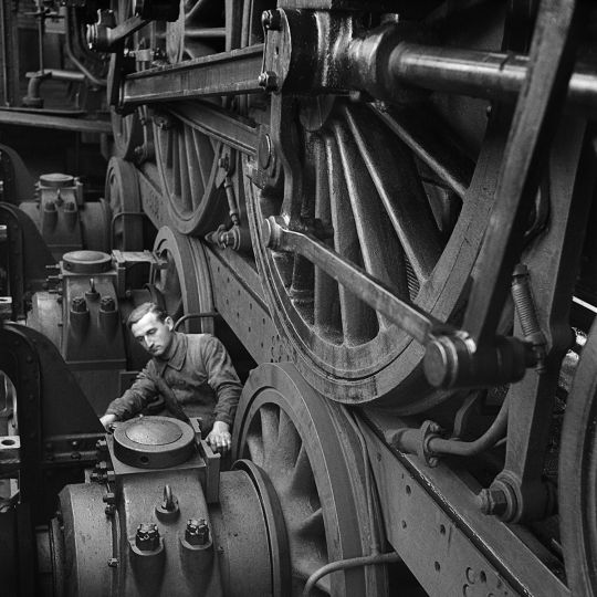 Ouvrier dans un atelier ferroviaire, travaillant sur le mécanisme d'une locomotive à vapeur. France, vers 1945. © Gaston Paris / Roger-Viollet