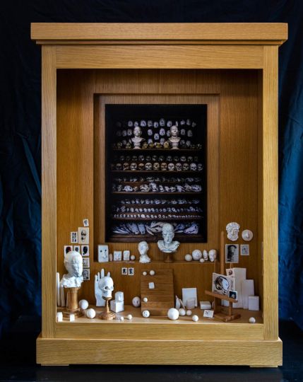 Ecce Homo II, 2021 Boîte en bois et plexiglas Photographie : Galerie Huguier, École des Beaux-Arts de Paris, Paris, 2016 Tirage jet d’encre sur papier baryté Hahnemüle, dessins, chevalet et escalier en bois, têtes, boules et crânes en faïence émaillée et socles en bois, LED