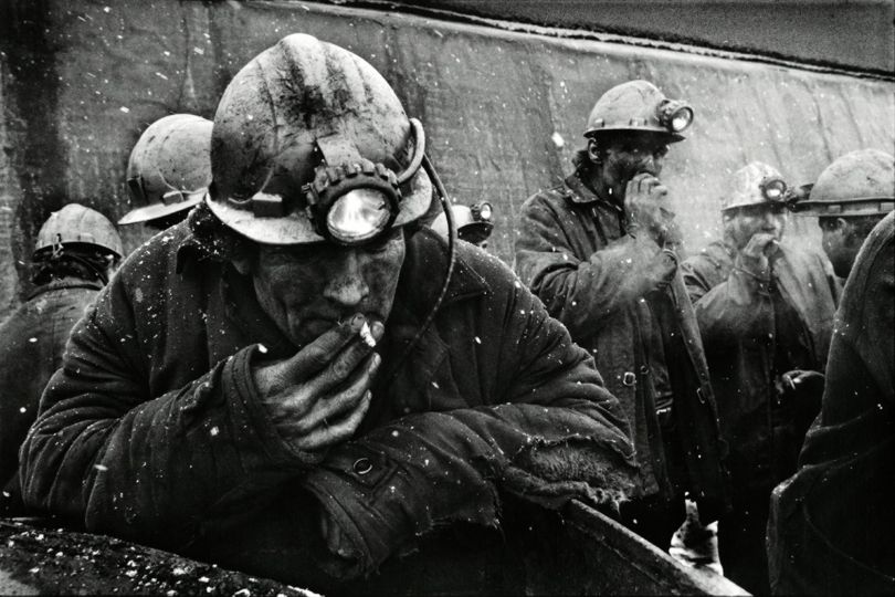 Shepard Sherbell (American, 1944-2018). At the end of an eight-hour shift underground in the Zhdanovskaya Coal Mine, half the time spent crawling on their hands and knees in cool dust, for the equivalent of $30 a month. The miners are smoking the second half of the cigarettes they lit this morning, then pinched out to save for this moment. Donbass region, Ukraine. February 1992. Gelatin silver print; 11 x 14 in. © Estate of Shepard Sherbell / Courtesy of MUUS Collection

