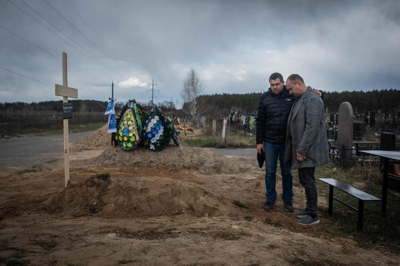 L'enterrement de Valentina, 82 ans, le 12 avril 2022. La femme est décédée pendant l'occupation russe dans la maison de retraite où elle vivait. Après le retrait des troupes, les corps de six de ses résidents, dont celui de Valentina, ont été retrouvés dans l'établissement. Devant sa tombe se trouve son fils, Anatoliy. Il a dit qu'à tout moment, les travailleurs des foyers de soins essayaient de prendre soin des personnes âgées. Mais faute d'électricité, d'eau, de gaz et de médicaments, et compte tenu de l'état de santé précaire de ces personnes, elles sont décédées les unes après les autres. / The burial of 82-year-old Valentina on April 12, 2022. The woman died during the Russian occupation in the nursing home where she lived. After the withdrawal of the troops, the bodies of six of its residents, including Valentina's, were found in the facility. In front of her grave is her son, Anatoliy. He said that at all times the nursing home workers tried to take care of the elderly. But due to the lack of electricity, water, gas, and medicines, and taking into account the precarious health of these people, they gradually died. © Santi Palacios / Revista 5W