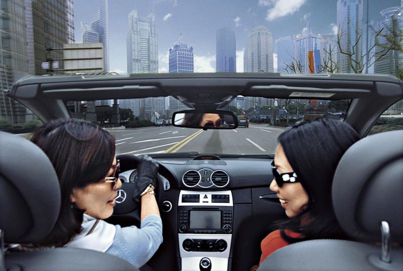 Young professional women Sara Si (driving) and Jennifer Cao enjoy a day out in the Pudong district, an area designated China's Wall Street, Shanghai, 2010. © HS Liu