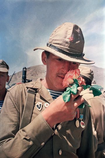 A Soviet soldier of the departing Soviet army when the Soviets pull out of Afghanistan, takes a moment to smell a rose. Kabul, 1988. © HS Liu