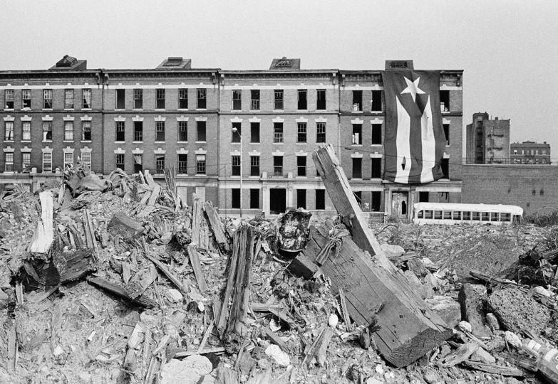 Charlotte St., The Bronx. 1980
Rubble in a vacant lot with four apartment buildings in the background. A large Puerto Rican ﬂag hangs from the rightmost building.
© Joe Conzo Jr


Rubble in a vacant lot with four apartment buildings in the background. A large Puerto Rican flag hangs from the rightmost building.

© Joe Conzo Jr.