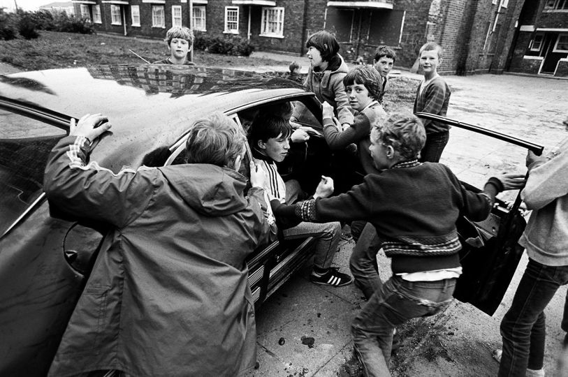 Children with abandoned / stolen car. Tommy White Gardens Everton, Liverpool 1981 © Mark Abrahams - Courtesy of Bluecoat Press