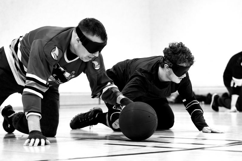 At goalball training, Montreal (Canada), December 1st 2023. Two teams of 3 players compete to score a goal against the opposing team. Players find their bearings using a sound-emitting ball and vibrations on the court. They wear opaque masks so that all athletes, whether visually impaired or totally blind, play under equal conditions. This also allows visually sighted individuals to participate in the practice. © Ophélie Chauvin