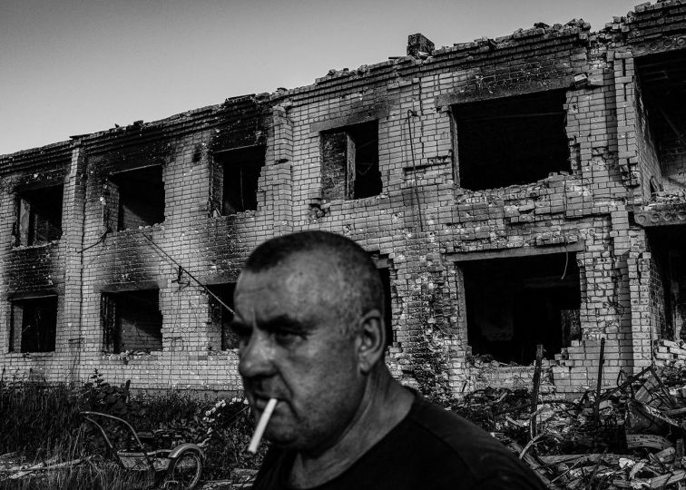 Yuri, 59, said he used to go to church and pray that all people live in peace. But recently, since the war, he “also started praying for Putin’s death.” He currently lives behind the building in his garage with his wife, Svetlana, who was recovering from wounds after being hit with shrapnel in her leg in another attack in the same village. June, 2022. © Byron Smith - From the book Testament ’22 - Courtesy Verlag Kettler