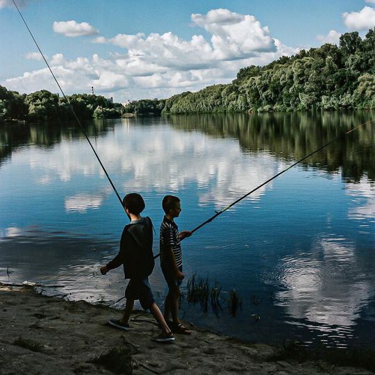 Amid the sounds of air-raid sirens boys fish on the Desna river, kilometers away from any nearby shelter. Chernihiv, July, 2022. © Byron Smith - From the book Testament ’22 - Courtesy Verlag Kettler