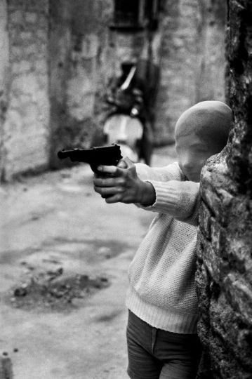 Near the Church of Santa Chiara. The killer’s game. (Vicino alla Chiesa di Santa Chiara. Il gioco del killer.) Palermo, 1982 © Courtesy Archivio Letizia Battaglia and The Photographers' Gallery