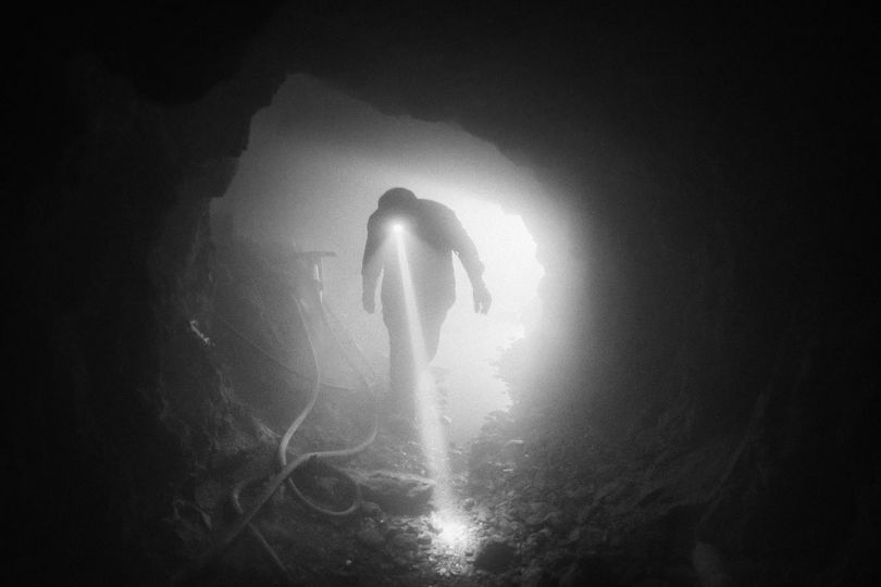 Nuristan, Afghanistan, May 2023: A worker walks inside a gemstone mine after a charge was detonated to open a new passage. Afghan miners collect gemstones and discard the lithium- bearing rocks. © Lorenzo Tugnoli