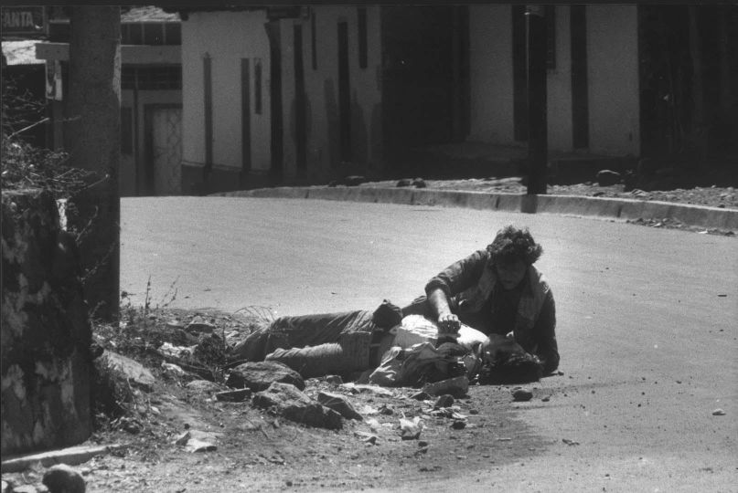Salvador, 1982. L'armée tente de lutter depuis deux ans contre la guérilla qui ne cesse de progresser, le photographe français Olivier Rebbot, mortellement touché dans le village de San Francisco de Goteira est secouru par l'Américain Harry Mattison. © Benoit Gysembergh