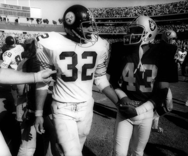 Michael Zagaris - Franco Harris of the Pittsburgh Steelers and George Atkinson of the Oakland Raiders following a tense game, 1976 © Michael Zagaris